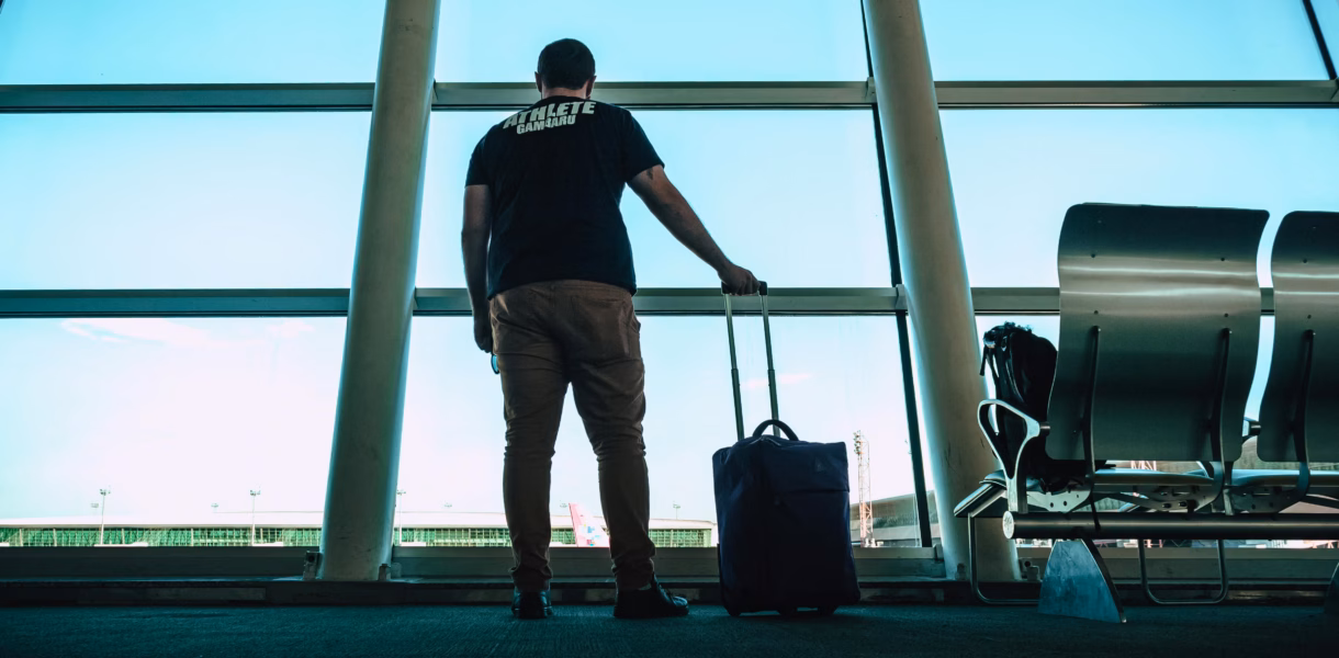a man in an airport carrying a carry on luggage