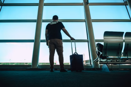 a man in an airport carrying a carry on luggage