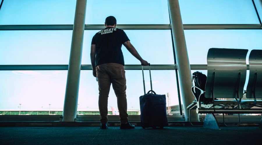 a man in an airport carrying a carry on luggage