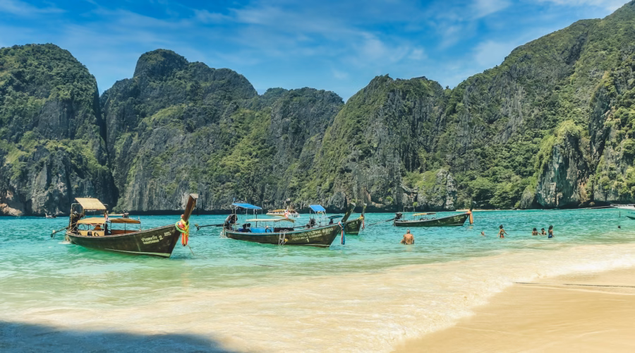Best time to visit Thailand tropical beach with longtail boats during perfect weather season