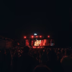 Crowd watching a concert on a stage at night.