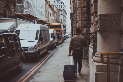 man holding luggage walking near road during daytime