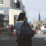 Woman wearing striped shirt holding phone on side of street