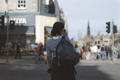 Woman wearing striped shirt holding phone on side of street