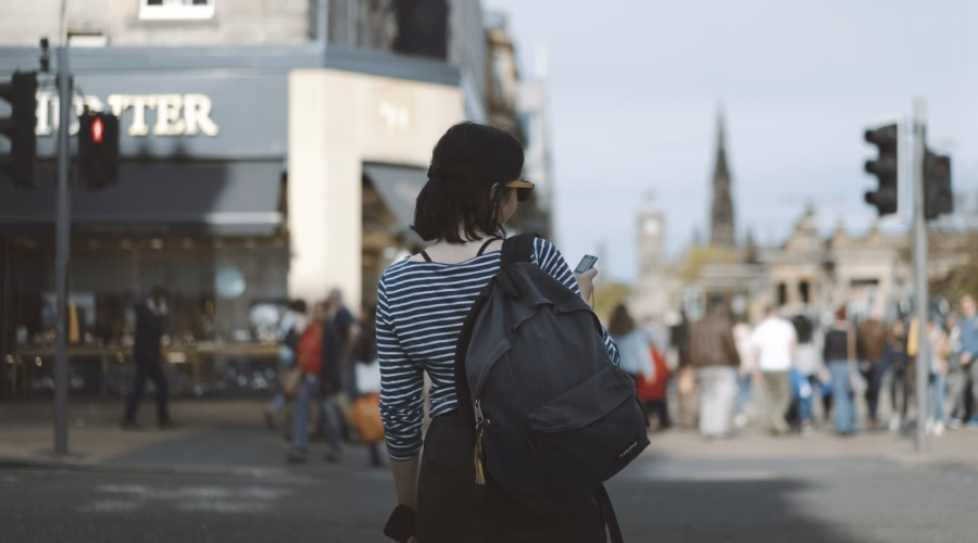 Woman wearing striped shirt holding phone on side of street