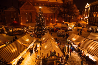 Lit-up Christmas market stalls in a historic town at night