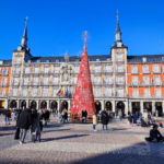 People gathered around a red Christmas tree in Madrid