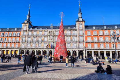 People gathered around a red Christmas tree in Madrid