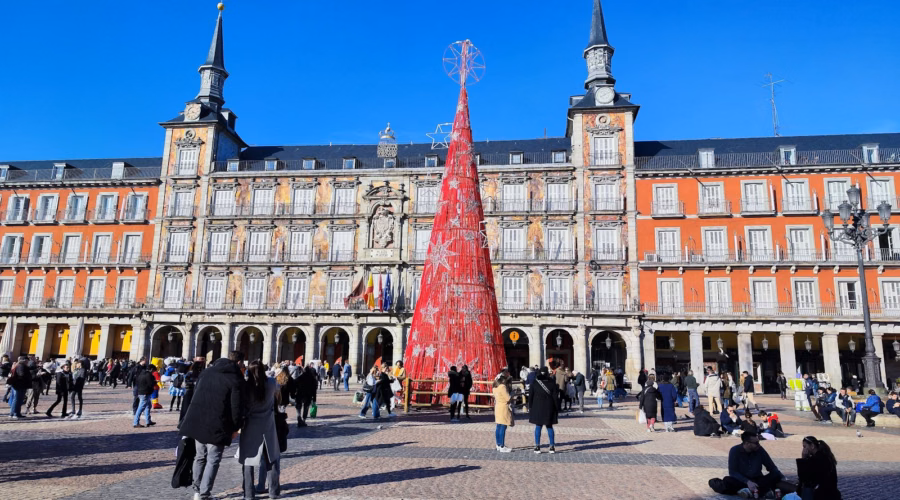 People gathered around a red Christmas tree in Madrid