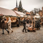 People walking between Christmas market stalls in the evening