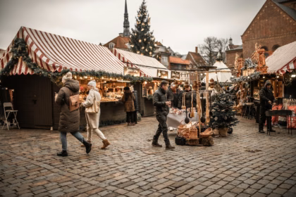 People walking between Christmas market stalls in the evening