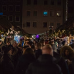 Crowds walking through a German Christmas market at night