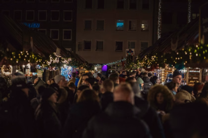 Crowds walking through a German Christmas market at night