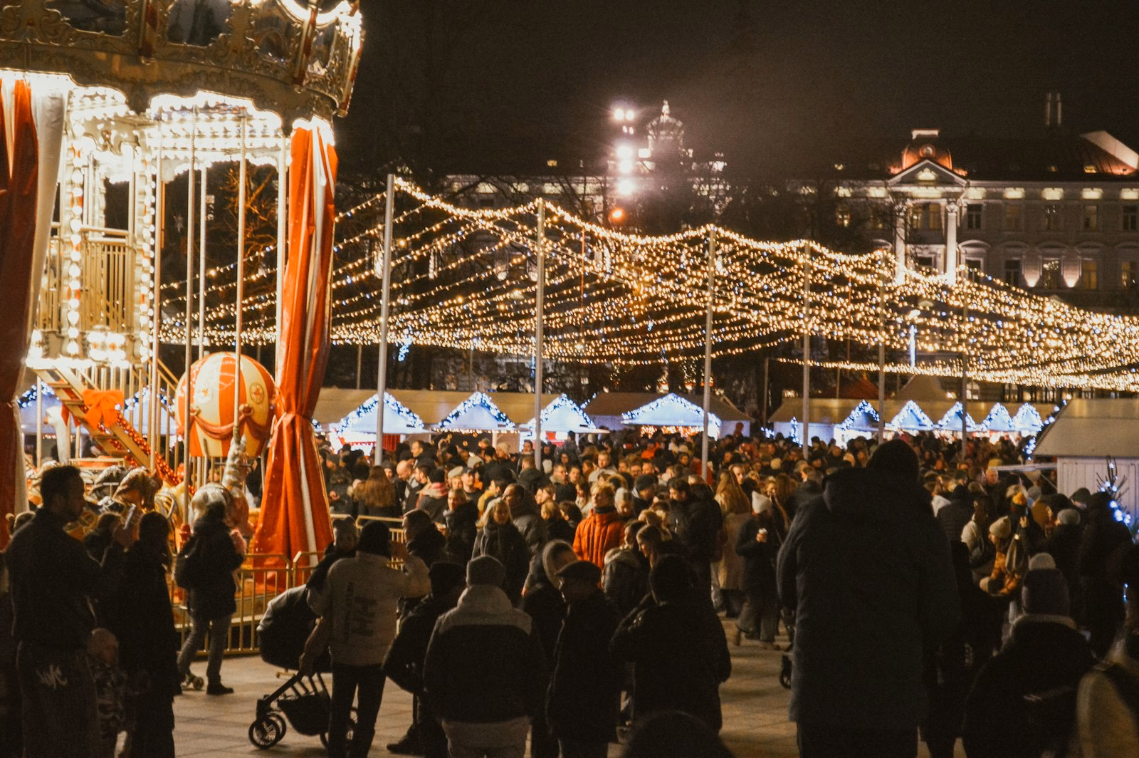 Crowds and the carousel at the Vilnius Christmas market at night